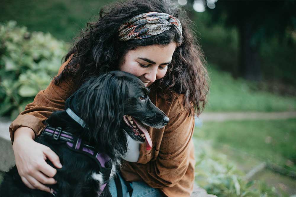 Happy woman cuddling black dog