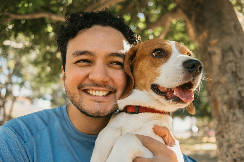 Man smiling holding beagle dog