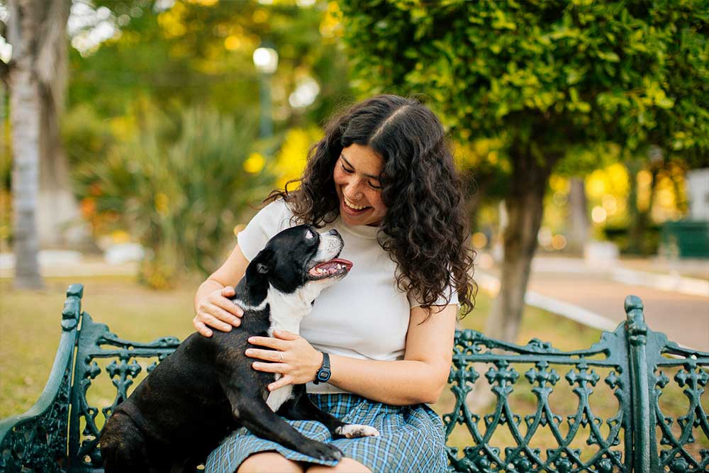 Smiling woman, dog, park bench